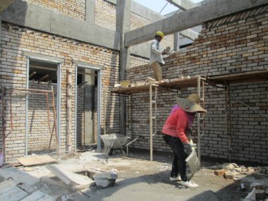 Johor, Malezya - 25 Kasım 2016: İnşaat alanında inşaat duvarları oluşturmak için tuğla döşeyen tuğla ustası. 
