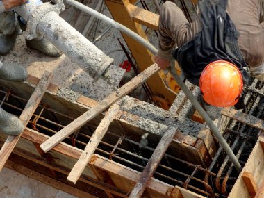 KUALA LUMPUR, MALAYSIA - 16 Mayıs 2017: İnşaat işçileri inşaat alanındaki kereste formuna beton pompa kullanarak ıslak beton döken bir grup işçi.  