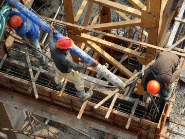 KUALA LUMPUR, MALAYSIA - 16 Mayıs 2017: İnşaat işçileri inşaat alanındaki kereste formuna beton pompa kullanarak ıslak beton döken bir grup işçi.  