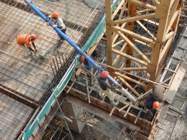 KUALA LUMPUR, MALAYSIA - 16 Mayıs 2017: İnşaat işçileri inşaat alanındaki kereste formuna beton pompa kullanarak ıslak beton döken bir grup işçi.  