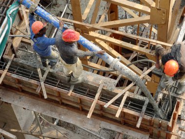 KUALA LUMPUR, MALAYSIA - 16 Mayıs 2017: İnşaat işçileri inşaat alanındaki kereste formuna beton pompa kullanarak ıslak beton döken bir grup işçi.  