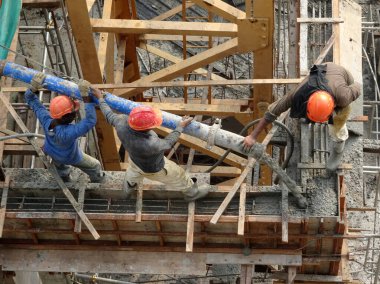 KUALA LUMPUR, MALAYSIA - 16 Mayıs 2017: İnşaat işçileri inşaat alanındaki kereste formuna beton pompa kullanarak ıslak beton döken bir grup işçi.  