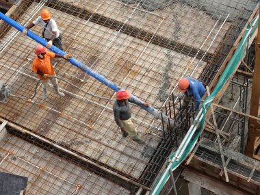 KUALA LUMPUR, MALAYSIA - 16 Mayıs 2017: İnşaat işçileri inşaat alanındaki kereste formuna beton pompa kullanarak ıslak beton döken bir grup işçi.  