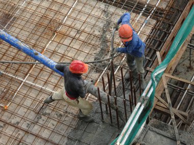 KUALA LUMPUR, MALAYSIA - 16 Mayıs 2017: İnşaat işçileri inşaat alanındaki kereste formuna beton pompa kullanarak ıslak beton döken bir grup işçi.  