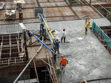 KUALA LUMPUR, MALAYSIA - 16 Mayıs 2017: İnşaat işçileri inşaat alanındaki kereste formuna beton pompa kullanarak ıslak beton döken bir grup işçi.  