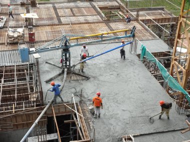 KUALA LUMPUR, MALAYSIA - 16 Mayıs 2017: İnşaat işçileri inşaat alanındaki kereste formuna beton pompa kullanarak ıslak beton döken bir grup işçi.  