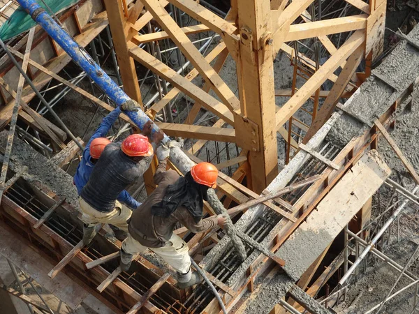 KUALA LUMPUR, MALAYSIA - 16 Mayıs 2017: İnşaat işçileri inşaat alanındaki kereste formuna beton pompa kullanarak ıslak beton döken bir grup işçi.  