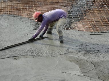 KUALA LUMPUR, MALAYSIA -SEPTEMBER 05, 2017: Construction workers leveling wet concrete has been poured. They also using long trowel for this job. 