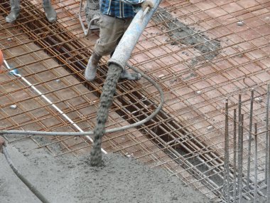 KUALA LUMPUR, MALAYSIA -SEPTEMBER 24, 2017: Construction workers pouring wet concrete using a hose from the elephant crane or concrete pump crane at the construction site.