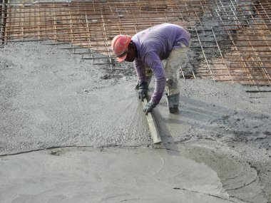 KUALA LUMPUR, MALAYSIA -SEPTEMBER 05, 2017: Construction workers leveling wet concrete has been poured. They also using long trowel for this job. 