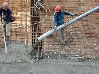 KUALA LUMPUR, MALAYSIA -SEPTEMBER 24, 2017: Construction workers pouring wet concrete using a hose from the elephant crane or concrete pump crane at the construction site.