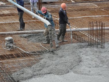 KUALA LUMPUR, MALAYSIA -SEPTEMBER 24, 2017: Construction workers pouring wet concrete using a hose from the elephant crane or concrete pump crane at the construction site.