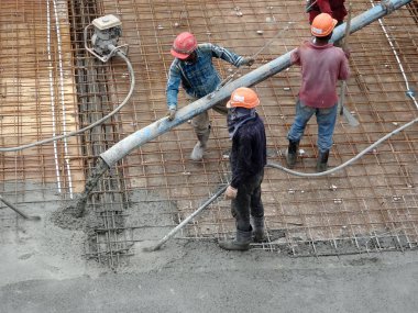 KUALA LUMPUR, MALAYSIA -SEPTEMBER 24, 2017: Construction workers pouring wet concrete using a hose from the elephant crane or concrete pump crane at the construction site.