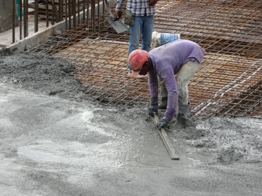 KUALA LUMPUR, MALAYSIA -SEPTEMBER 05, 2017: Construction workers leveling wet concrete has been poured. They also using long trowel for this job. 