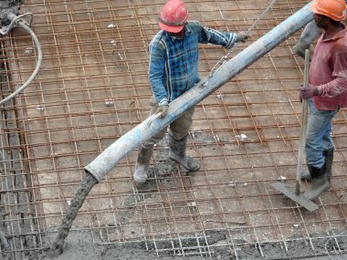 KUALA LUMPUR, MALAYSIA -SEPTEMBER 24, 2017: Construction workers pouring wet concrete using a hose from the elephant crane or concrete pump crane at the construction site.