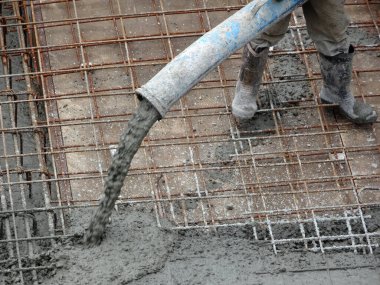 KUALA LUMPUR, MALAYSIA -SEPTEMBER 24, 2017: Construction workers pouring wet concrete using a hose from the elephant crane or concrete pump crane at the construction site.