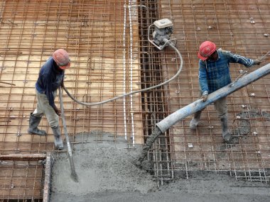 KUALA LUMPUR, MALAYSIA -SEPTEMBER 24, 2017: Construction workers pouring wet concrete using a hose from the elephant crane or concrete pump crane at the construction site.