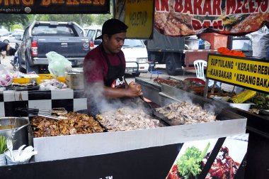 Kuala Lumpur, Malezya - 24 Ocak 2020: Sokak satıcıları halka yerel gıda satar. Yoldan geçenlere, kulübelerine uğramaları için seslendiler..
