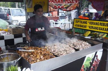 Kuala Lumpur, Malezya - 24 Ocak 2020: Sokak satıcıları halka yerel gıda satar. Yoldan geçenlere, kulübelerine uğramaları için seslendiler..