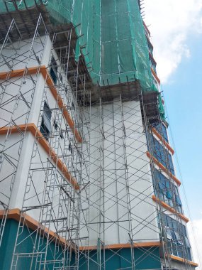 Kuala Lumpur, Malezya -16 Temmuz 2019: Yüksek katlı bina inşaatı sırasında binanın dış cephesinde platform ve güvenlik ağlarını yakalayın. Bireyleri ve malları düşen enkazlardan korur. 