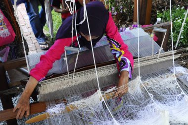 Kuala Lumpur, Malezya - 6 Eylül 2017: Bir kadın şarkı sözü örmek için geleneksel dokuma makineleri kullanıyor. Songket, yüksek kaliteli ve değerli geleneksel Malezya giysisidir..