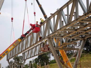 Seremban, Malezya -3 Haziran 2017: İnşaat işçileri inşaat alanında yüksek seviyede çalışırken seyyar vinç kovasında duruyorlar. Uygun güvenlik giysileri giyiyorlar.. 