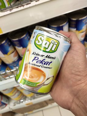 Kuala Lumpur, Malezya - 22 Aralık 2019: Şekerli süt ve buharlaştırılmış süt kutuları. Süpermarketin içindeki rafta satılık. Ana bileşen palmiye yağı tohumlarından yapılır..
