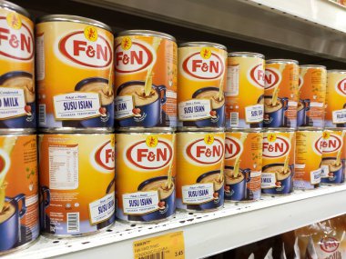 Kuala Lumpur, Malezya - 22 Aralık 2019: Şekerli süt ve buharlaştırılmış süt kutuları. Süpermarketin içindeki rafta satılık. Ana bileşen palmiye yağı tohumlarından yapılır..