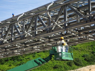 Seremban, Malezya -3 Haziran 2017: İnşaat işçileri inşaat alanında yüksek seviyede çalışırken seyyar vinç kovasında duruyorlar. Uygun güvenlik giysileri giyiyorlar.. 