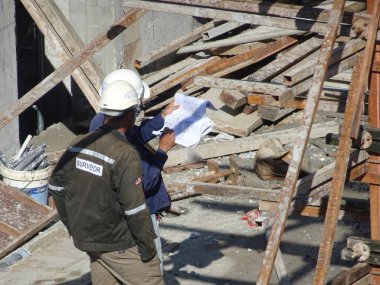 Kuala Lumpur, Malezya - 29 Mart 2017: İnşaat işçileri inşaat alanındaki çizimleri tartışıyor ve atıfta bulunuyorlar 