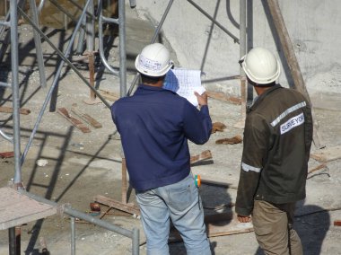 Kuala Lumpur, Malezya - 29 Mart 2017: İnşaat işçileri inşaat alanındaki çizimleri tartışıyor ve atıfta bulunuyorlar 