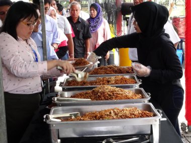 KUALA LUMPUR, MALAYSIA -MARCH 5, 2020: Street vendors sell local food to the public. They called to the passersby to stop by their booth.