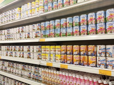 Kuala Lumpur, Malezya - 22 Aralık 2019: Şekerli süt ve buharlaştırılmış süt kutuları. Süpermarketin içindeki rafta satılık. Ana bileşen palmiye yağı tohumlarından yapılır..