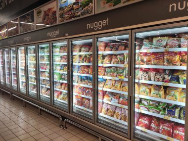 KUALA LUMPUR, MALAYSIA -MARCH 16, 2020: Packed chicken nugget in various brand placed in display chiller refrigerator inside the huge supermarket.