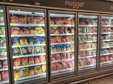 KUALA LUMPUR, MALAYSIA -MARCH 16, 2020: Packed chicken nugget in various brand placed in display chiller refrigerator inside the huge supermarket.