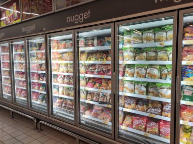 KUALA LUMPUR, MALAYSIA -MARCH 16, 2020: Packed chicken nugget in various brand placed in display chiller refrigerator inside the huge supermarket.