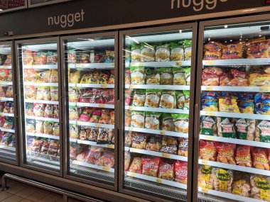 KUALA LUMPUR, MALAYSIA -MARCH 16, 2020: Packed chicken nugget in various brand placed in display chiller refrigerator inside the huge supermarket.