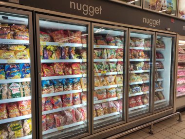 KUALA LUMPUR, MALAYSIA -MARCH 16, 2020: Packed chicken nugget in various brand placed in display chiller refrigerator inside the huge supermarket.
