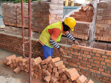 SEREMBAN, MALAYSIA - 15 Mart 2020: İnşaat işçilerinin inşaat alanında yaptığı tuğla işi. İşçiler kil tuğla döşeyip duvar oluşturmak için harç kullandılar.. 