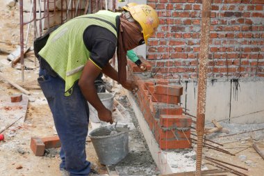 SEREMBAN, MALAYSIA - 15 Mart 2020: İnşaat işçilerinin inşaat alanında yaptığı tuğla işi. İşçiler kil tuğla döşeyip duvar oluşturmak için harç kullandılar.. 