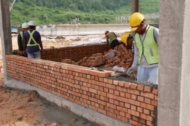 SEREMBAN, MALAYSIA - 15 Mart 2020: İnşaat işçilerinin inşaat alanında yaptığı tuğla işi. İşçiler kil tuğla döşeyip duvar oluşturmak için harç kullandılar.. 