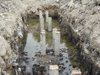 İnşaat alanında kare şeklinde beton yığını. Beton kazık makinesiyle toprağa sürülmüş.. 