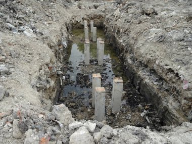 İnşaat alanında kare şeklinde beton yığını. Beton kazık makinesiyle toprağa sürülmüş.. 