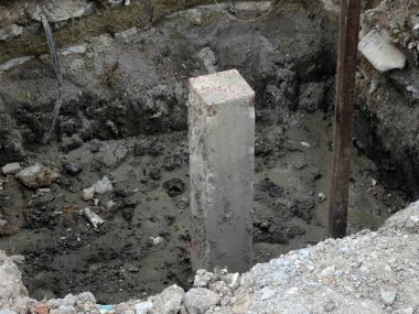 İnşaat alanında kare şeklinde beton yığını. Beton kazık makinesiyle toprağa sürülmüş.. 