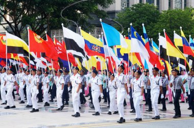 PUTRAJAYA, MALAYSIA - 31 AĞUSTOS 2019: Malezyalı gençler, Malezya devlet bayraklarını tutarken yolda yürüyen üniformalarla tamamlandı. Üniformalar Malezya 'daki çeşitli üniformaları temsil ediyordu.