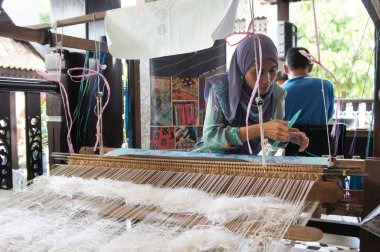 KUALA LUMPUR, Malezya - Kasım 29. 2018: Bir kadın şarkı sözü dokumak için geleneksel dokuma makineleri kullanıyor. Songket, yüksek kaliteli ve değerli geleneksel Malezya giysisidir..