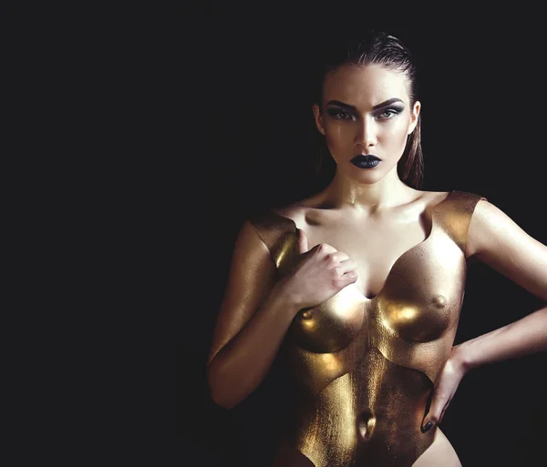 La chica en un corsé de metal dorado en el estudio sobre un fondo negro . —  Fotos de Stock