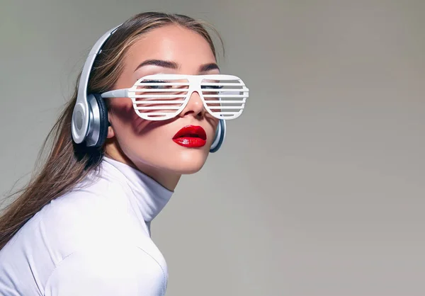 Una hermosa chica en gafas blancas con grandes auriculares blancos y cabello suelto, escuchando música . —  Fotos de Stock