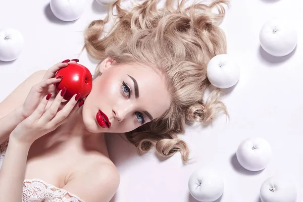 Ung vacker blond tjej med ljus hy och röda rockar ligger på vit bakgrund. — Stockfoto