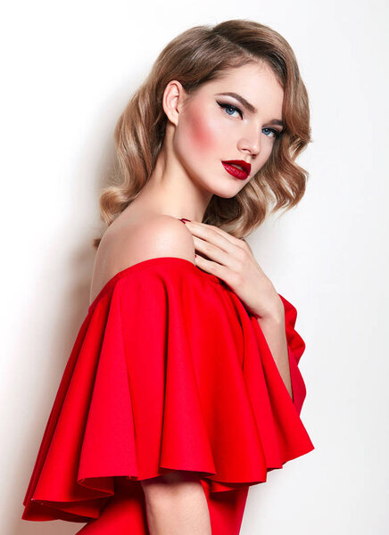 На фоне цветущих жёлтых кустов рододендрона стоит красивая девушка с текучими волнистыми каштановыми волосами. Естественный макияж, красные губы. Пушистое платье. Красота. Здоровье, мода. Природа
.